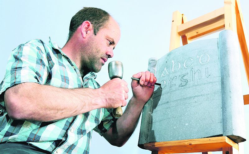 Cormac, a skilled lettercarver, working on an Irish language alphabet