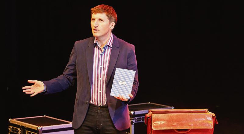 Dr Mark Rowe on stage with some of his props during A Prescription for Happiness.