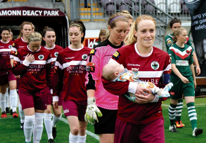 Meadbh de Burca carries her 6-weeks old nephew Iarlaith onto the field as mascot for the team's WNL match with Cork City WFC in Eamon Deacy Park at the weekend. He may have brought them luck as they won 3-0 and Auntie Meadbh scored one of the goals! She also earned a call up to the Irish squad: Photo by Eirefoto