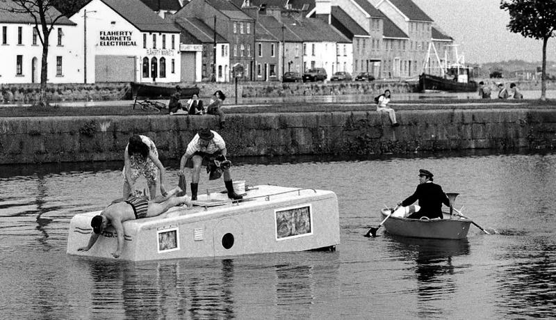 Members of the Dutch company Vis a Vis perform on their sunken campervan in a promotional scene from their survival comedy, Drift, in the Claddagh Basin for the Galway Arts Festival in July 1997. The comic spectacle was held at the Festival Big Top on a set imersed in a giant tank containing 57,000 gallons of water.
